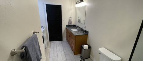 Et lille badeværelse med toilet, vask og spejl.