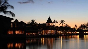 A resort with multiple buildings, a pool, and palm trees at dusk. - Waikoloa Saltwater Haven in Vistas (Waikoloa)