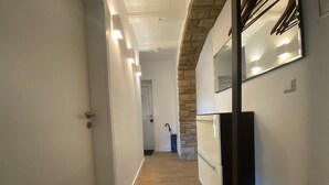 A hallway with a wooden floor, a stone accent wall, and a modern kitchen area with a refrigerator and cabinets. - Alter Ziegelhof Vechta (Vechta)