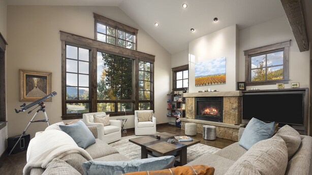 Un salón espacioso con un sofá seccional grande, una chimenea y ventanas amplias con vistas al exterior.