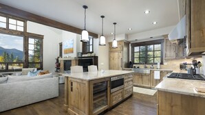 Cocina amplia con armarios de madera, una isla central e iluminación colgante.