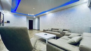 Ein modernes Wohnzimmer mit einer Eckcouch, einem weißen Couchtisch und einem grauen Sessel.