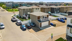 Een woonwijk met moderne huizen, een parkeerplaats en een heldere lucht.