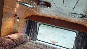 Interior acogedor de una autocaravana con una cama, una ventana y un respiradero en el techo.
