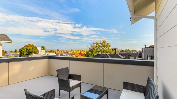 A balcony with wicker furniture and a clear view of the cityscape.