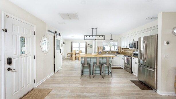 Een moderne keuken met witte kastjes, roestvrijstalen apparatuur en een centraal eiland met barkrukken.