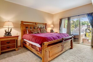 A bedroom with a wooden bed, two bedside tables, a nightstand, and a view of the outdoors through a sliding glass door. - Downtown WP River Villa 582 I Private Hot Tub I Great Views I Bunk Room I Discounted Attractions (Winter Park)