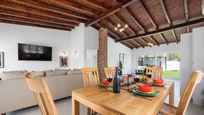 A dining area with a wooden table, chairs, and a brick pillar. - 2BR Countryside Home w/ Sea Views & Private Pool (Noord)