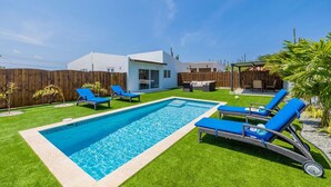A backyard with a swimming pool, blue lounge chairs, and a wooden fence. - 2BR Countryside Home w/ Sea Views & Private Pool (Noord)