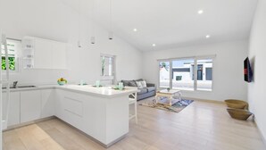 A modern kitchen with white cabinetry, a central island, and a dining area with a sofa and coffee table. - 4BR4BA w/ Private Pool ~ Walking distance to Ritz (Noord)
