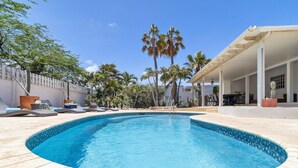A swimming pool with lounge chairs and a covered patio area. - 4BR4BA w/ Private Pool ~ Walking distance to Ritz (Noord)