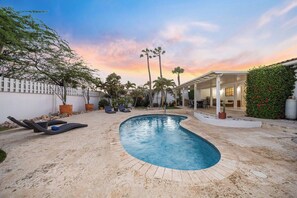 A swimming pool with lounge chairs, surrounded by palm trees and a white fence. - 4BR4BA w/ Private Pool ~ Walking distance to Ritz (Noord)