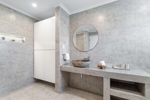 A modern bathroom with grey tiles, a round mirror, a stone basin, and a white cabinet. - 4BR4BA w/ Private Pool ~ Walking distance to Ritz (Noord)