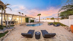 A backyard with a swimming pool, lounge chairs, and a dining area. - 4BR4BA w/ Private Pool ~ Walking distance to Ritz (Noord)
