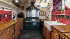 Une cuisine équipée d’une cuisinière, d’un évier, de meubles en bois et de murs carrelés en rouge et en vert.