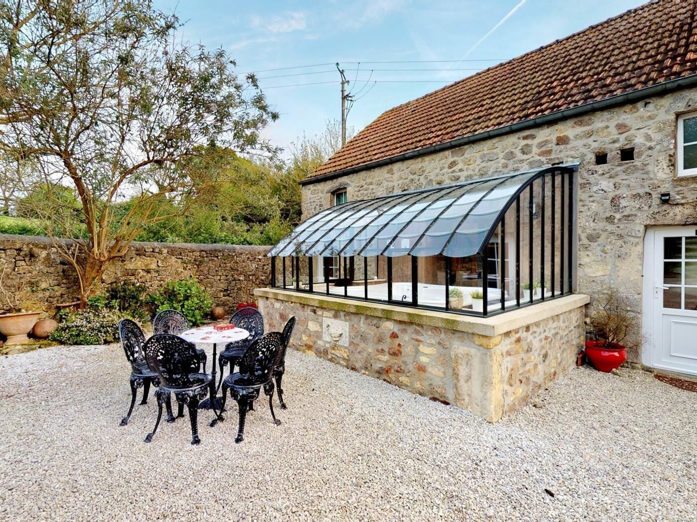 Un bâtiment en pierre doté d’un patio couvert, d’un espace extérieur aménagé pour s’asseoir et d’un sol en gravier.