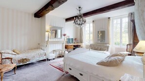 Une chambre à coucher avec un grand lit, un bureau, une chaise, une commode et un lustre.