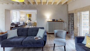 Un salón amplio con sofá, sillas, una mesa de comedor y una cocina al fondo.