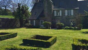 A stone building with a large lawn and hedges.