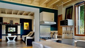 Cozinha moderna com área de jantar, piso de madeira e televisão na parede.