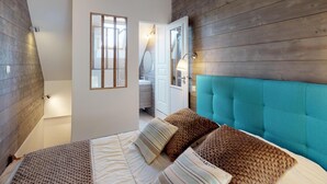 Ein Schlafzimmer mit Bett, Fenster, Tür und einem sichtbaren Badezimmer im Hintergrund.