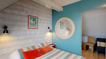 A bedroom with a bed, a round mirror, a wall-mounted lamp, and a framed picture.
