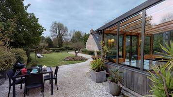 A modern outdoor dining area with a table and chairs, surrounded by gravel and potted plants.