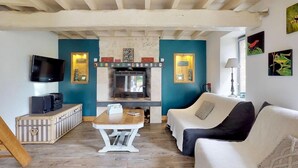 Un salon avec une cheminée, un téléviseur, un canapé et une table.