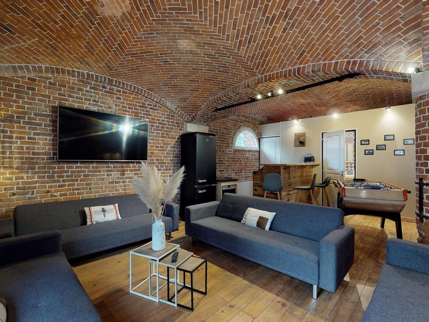 A cozy living room with brick walls, a flat-screen TV, a sofa, a coffee table, and a fireplace.