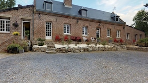 Un bâtiment en briques avec une allée en gravier et un espace extérieur aménagé pour s’asseoir.