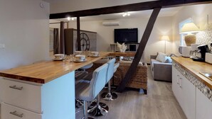 Une cuisine moderne avec un îlot central en bois, des chaises de salle à manger, un canapé et un téléviseur.