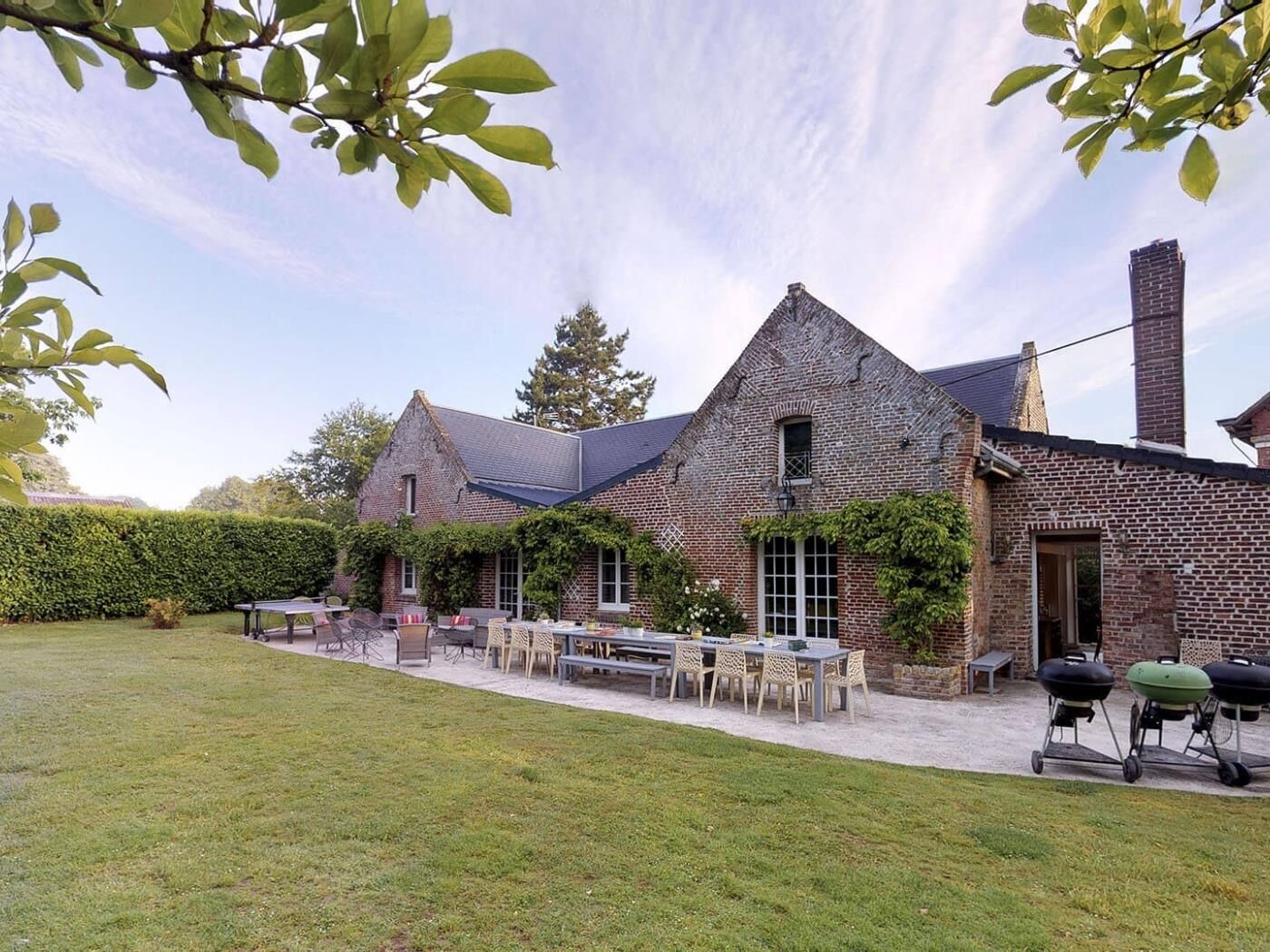 A brick house with a patio, outdoor furniture, and a grill.