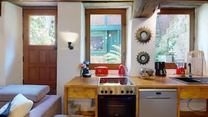 A compact kitchen with a wooden countertop, a stove, a dishwasher, and a window with a view of greenery. - Cour du paradis 8 pers : billiards, baby, 30 min sea (Villedieu-les-Poêles)