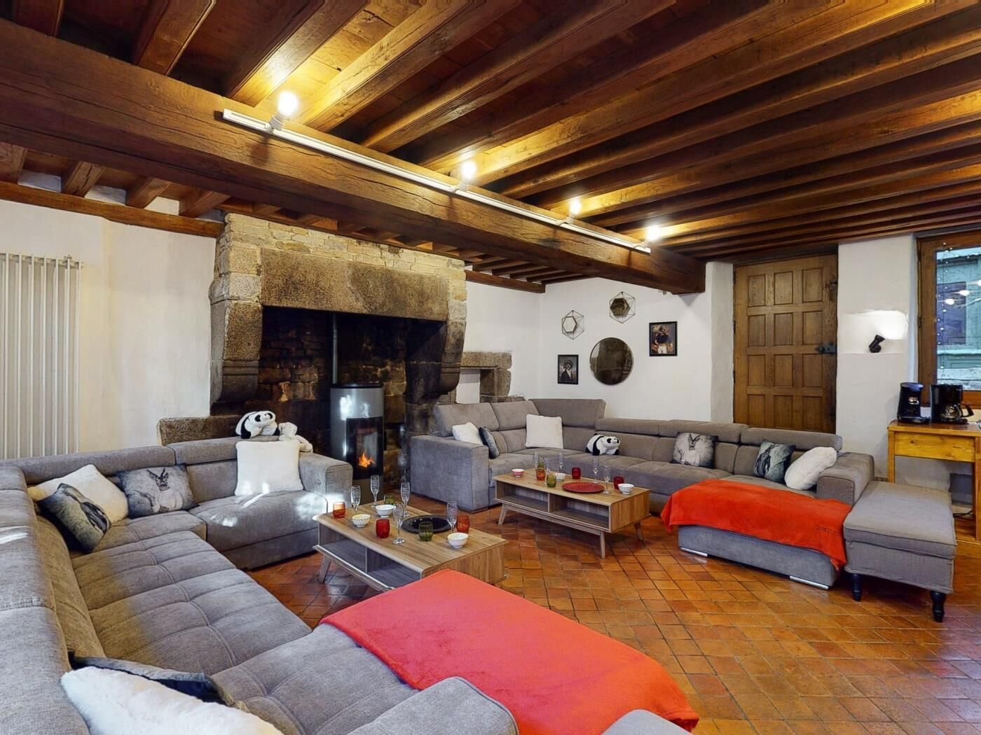 Una sala de estar acogedora con chimenea de piedra, vigas de madera y un amplio sofá modular.