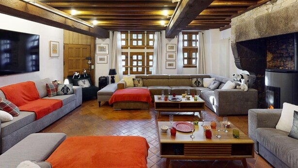 A cozy living room with a fireplace, wooden ceiling beams, and a large TV. - Cour du paradis 8 pers : billiards, baby, 30 min sea (Villedieu-les-Poêles)
