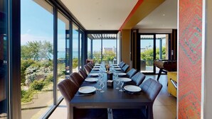A dining area with a long table, chairs, and a view of the outdoors.