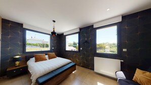A modern bedroom with a large bed, two windows, and a view of the outside.