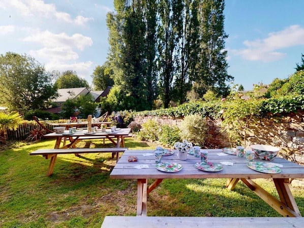 An outdoor setting with picnic tables set up in a garden.