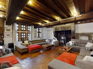 A cozy living room with a stone fireplace, wooden beams, and a large sofa set.