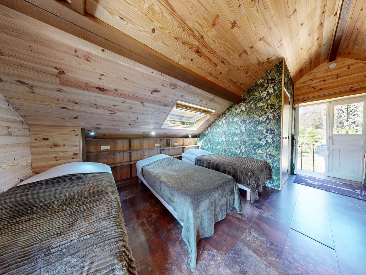 Eine Holzhütte mit zwei Betten, einem Oberlicht und einer Tür, die nach draußen führt.