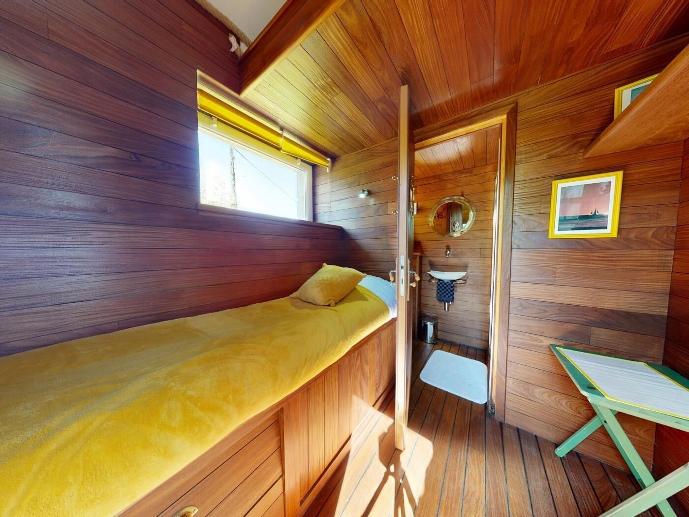 A compact cabin with a single bed, a small bathroom, and a window.
