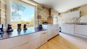 Une cuisine moderne avec un mur en pierre, un plan de travail en bois et une grande fenêtre donnant sur un paysage magnifique.