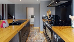 Eine moderne Küche mit einer Holzausziehtheke, schwarzen Geräten und einem Fliesenboden mit Muster.