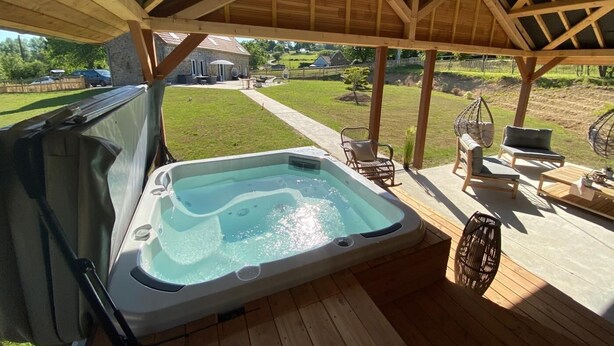 Ein Whirlpool unter einer Holzpergola mit Blick auf einen Garten.