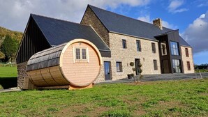Una casa con una estructura en forma de barril, paredes de piedra y un techo empinado.