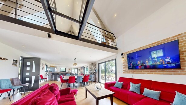 A spacious living area with a red sofa set, a dining area, and a kitchen in the background. - Concorde Aérogare 25 people 2 Cottage : jacuzzi baby airhockey (La Haye-Pesnel)