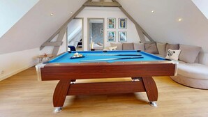 A pool table in a room with a sloped ceiling and a sofa. - Concorde Aérogare 25 people 2 Cottage : jacuzzi baby airhockey (La Haye-Pesnel)