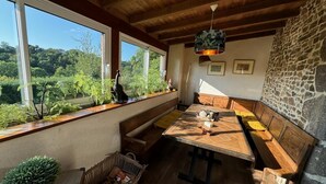 Ein gemütliches Zimmer mit Holztisch, Bänken, großen Fenstern und einer Steinwand.