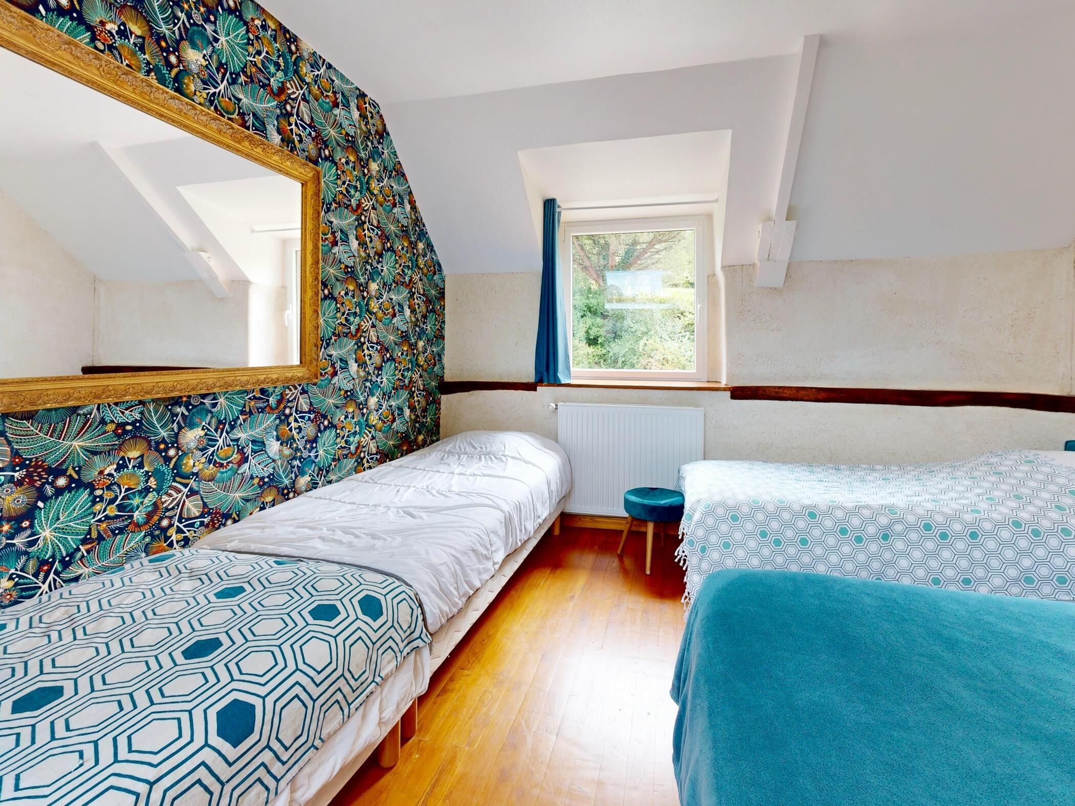 A bedroom with two beds, a window with a view, a radiator, and a mirror on the wall.