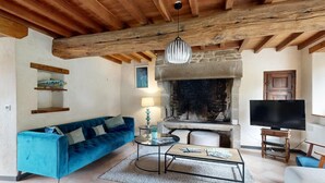 Ein Wohnzimmer mit blauem Sofa, Couchtisch, Kamin und Fernseher.